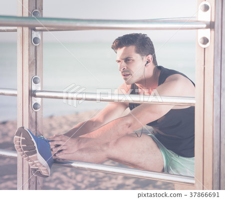 Male athlete stretching on outdoor fitness station Male athlete stretching on outdoor fitness station 37866691