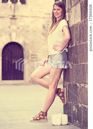 Young woman standing near old stone wall Young woman standing near old stone wall 37866806