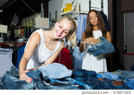two women picking new pair of jeans in fashion department 37867369