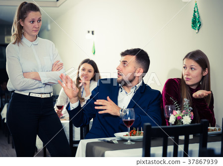Young woman is dissatisfied in time her boyfriend is talking with woman in restaurante Young woman is dissatisfied in time her boyfriend is talking with woman in restaurante 37867939