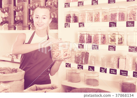 Young woman is offering dried fruits in container 37868134