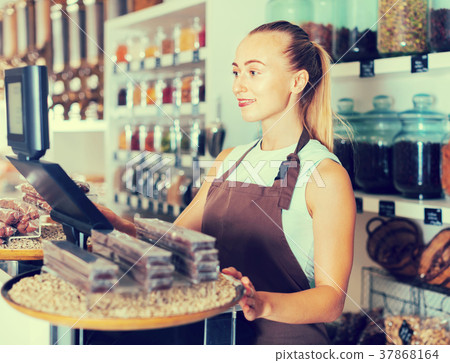 Young woman is standing near cashbox 37868164