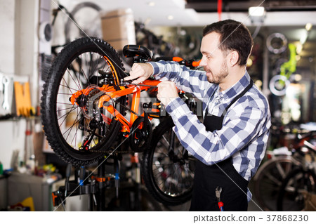 Man working on master mechanic assembling bicycle equipment 37868230