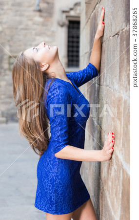 Elegant girl is posing in blue dress near old wall Elegant girl is posing in blue dress near old wall 37868265