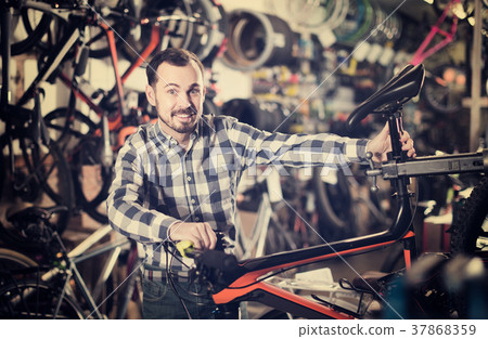 man checks bicycle handlebar in shop when choosing bike man checks bicycle handlebar in shop when choosing bike 37868359