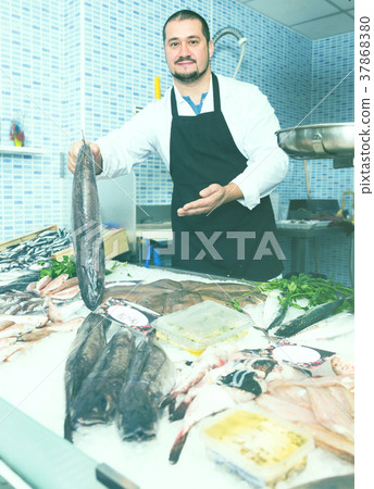 Man behind counter holding fish Man behind counter holding fish 37868380