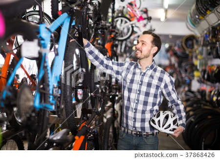 Sport racer is choosing in sports store convenient bike Sport racer is choosing in sports store convenient bike 37868426