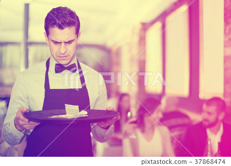 disgruntled waiter holding serving tray with tips disgruntled waiter holding serving tray with tips 37868474