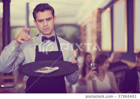 male waiter looking at a tip on a tray 37868481