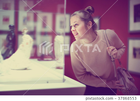 Young female visitor looking at exhibition in museum of ancient sculpture 37868553
