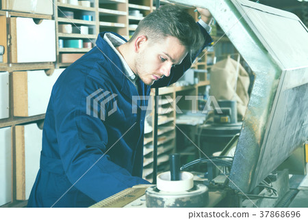 Young male joiner working with trimming machine 37868696