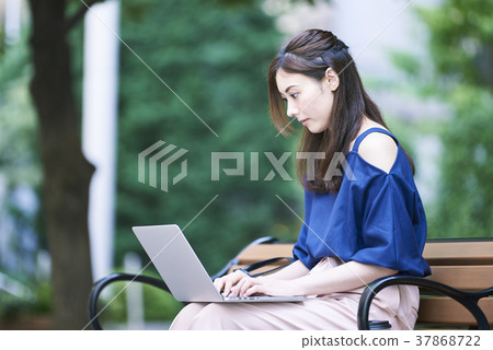 Woman using a PC on a bench Woman using a PC on a bench 37868722