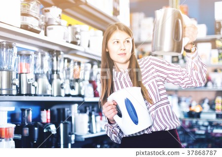 Young attractive woman choosing kettle in household appliances store 37868787