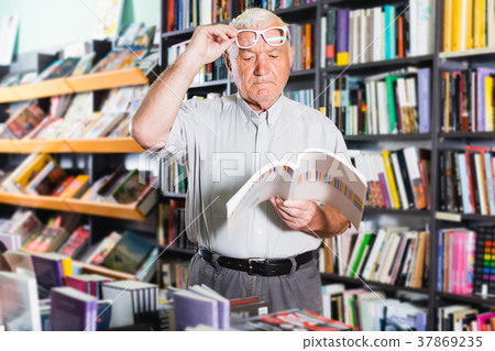 Man 61-67 years old is choosing book for reading in free time Man 61-67 years old is choosing book for reading in free time 37869235