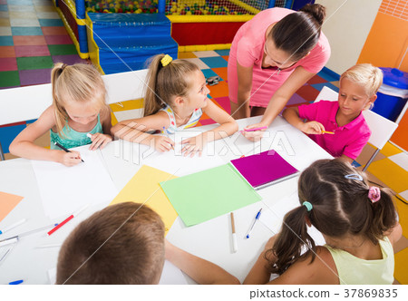 Group of children drawing on lesson with help of teacher 37869835