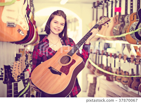 Nice teen girl examining various acoustic guitars 37870067
