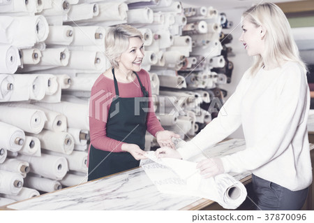 Aged seller is showing fabrics to young buyer 37870096