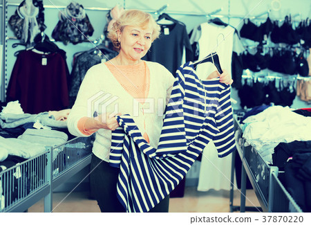Happy woman consumer choosing striped dress Happy woman consumer choosing striped dress 37870220