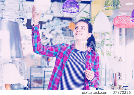 girl in lighter shop choosing modern glass chandelier for house interior 37870256