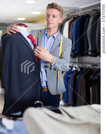 Seller in business clothes measuring jacket Seller in business clothes measuring jacket 37870300