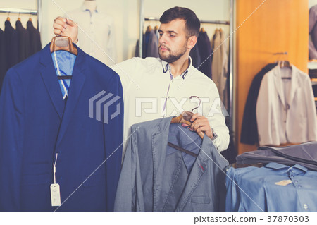 guy is considering an assortment of jackets 37870303