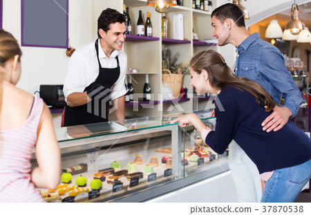 Smiling pastryman offering delicious to visitors Smiling pastryman offering delicious to visitors 37870538