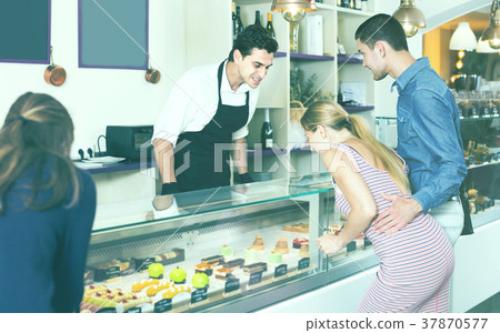 Positive man confectioner serving visitors Positive man confectioner serving visitors 37870577