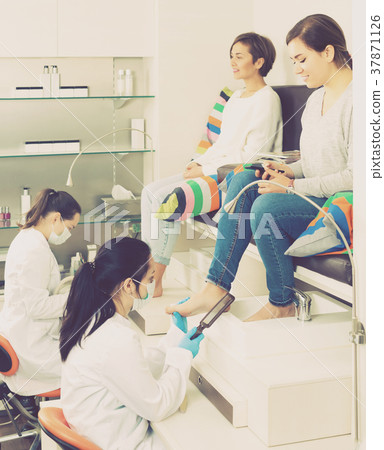 Woman relaxing in nail salon on pedicure and using phone Woman relaxing in nail salon on pedicure and using phone 37871126
