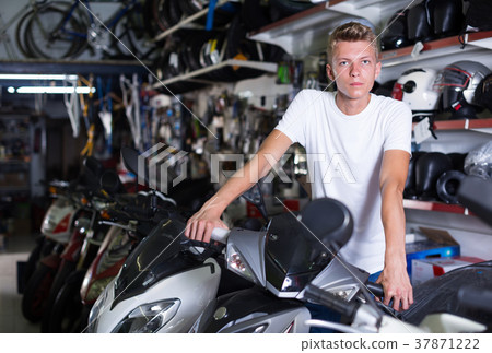 Portrait of young man with the motorbike in store 37871222