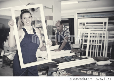 Young happy female worker with plastic window frame Young happy female worker with plastic window frame 37871235