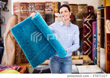 Cheerful woman consumer shopping and holding carpet indoors 37871327