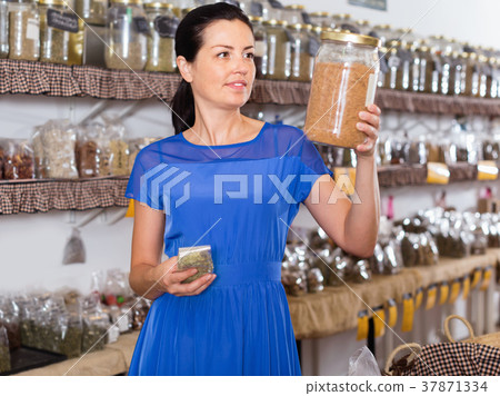 Woman choosing eco dried herbs sold by weight Woman choosing eco dried herbs sold by weight 37871334