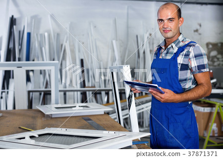 Focused workman in overalls controlling quality of assembly of plastic window in workshop Focused workman in overalls controlling quality of assembly of plastic window in workshop 37871371