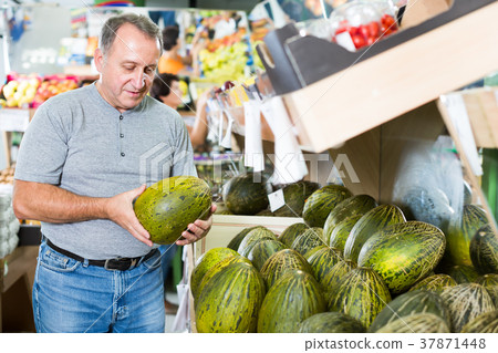 Nice man is choosing ripe melon in the store 37871448