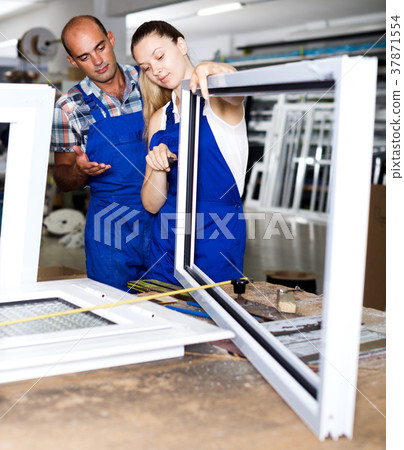 Female assembler of windows consulting with master 37871554
