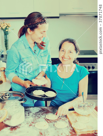 Two laughing women making pies 37871748