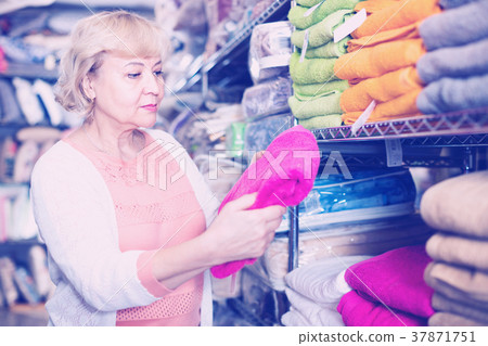 mature woman holding cotton colour towel in the textile shop mature woman holding cotton colour towel in the textile shop 37871751