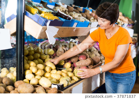 Nice woman is choosing potato in the store Nice woman is choosing potato in the store 37871837