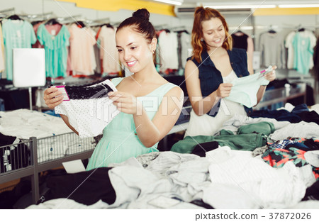 Positive women friends choosing trousers in shop Positive women friends choosing trousers in shop 37872026