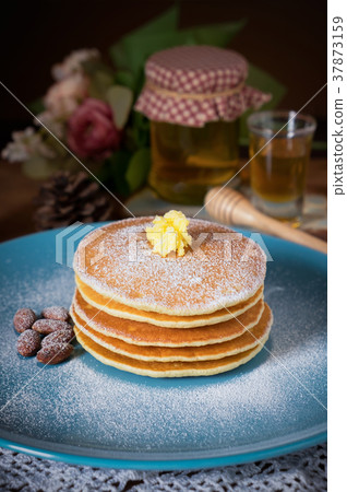 Pancakes with honey and almonds on blue plate  37873159