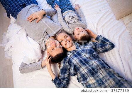 mom dad and son in the morning lying on the bed at 37877389