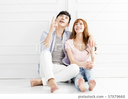 young couple sitting together and looking above young couple sitting together and looking above 37879668