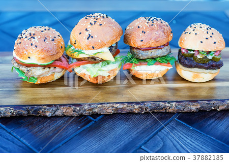 Four burgers on wooden board in restaurant Four burgers on wooden board in restaurant 37882185