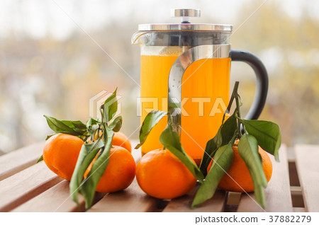Glass teapot with orange drink and tangerines Glass teapot with orange drink and tangerines 37882279