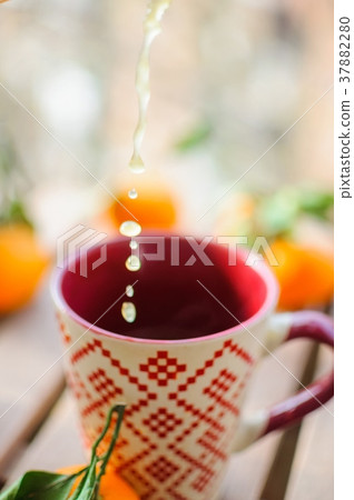 Pouring tangerine tea into cup on wooden table Pouring tangerine tea into cup on wooden table 37882280