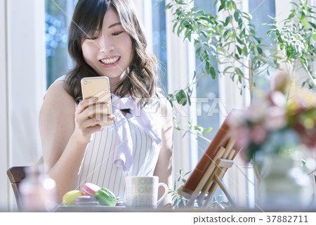 A woman who spends leisurely while using a smartphone A woman who spends leisurely while using a smartphone 37882711