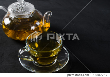 Cup of delicious herbal tea and glass teapot. Cup of delicious herbal tea and glass teapot. 37887257