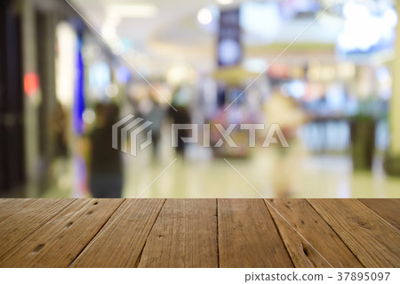 blur wood table on people walk in shopping centre blur wood table on people walk in shopping centre 37895097