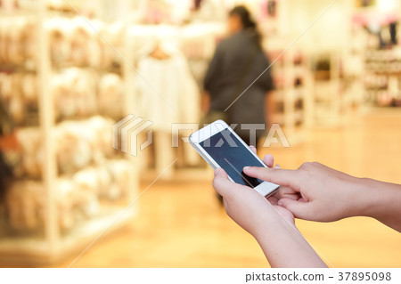 blur smart phone on people walk in shopping mall blur smart phone on people walk in shopping mall 37895098
