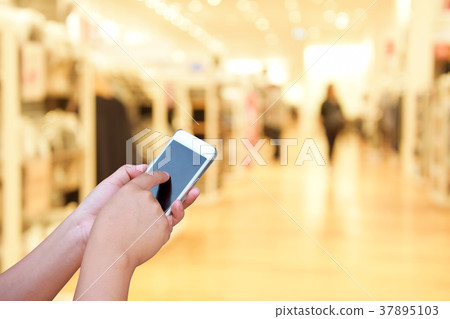 blur smart phone on people  walk in shopping mall 37895103